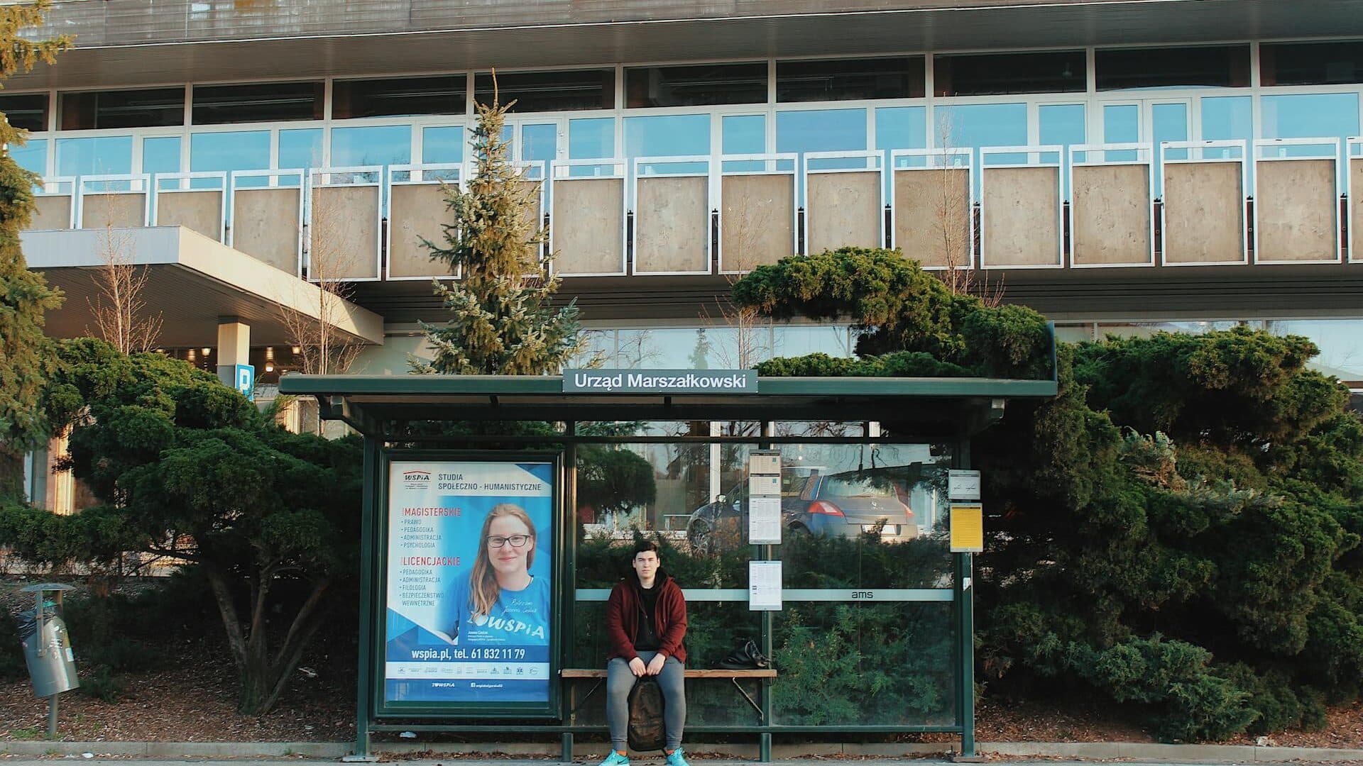 Illuminated bus shelter advertising panel on a UK high street at dusk