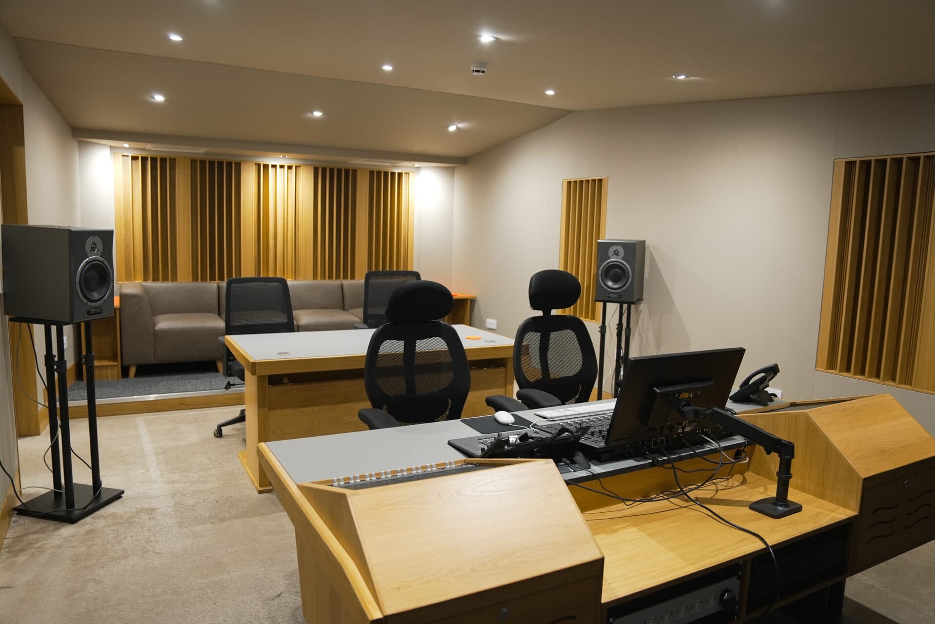 Second production room with mixing desk, monitors, and acoustic treatment